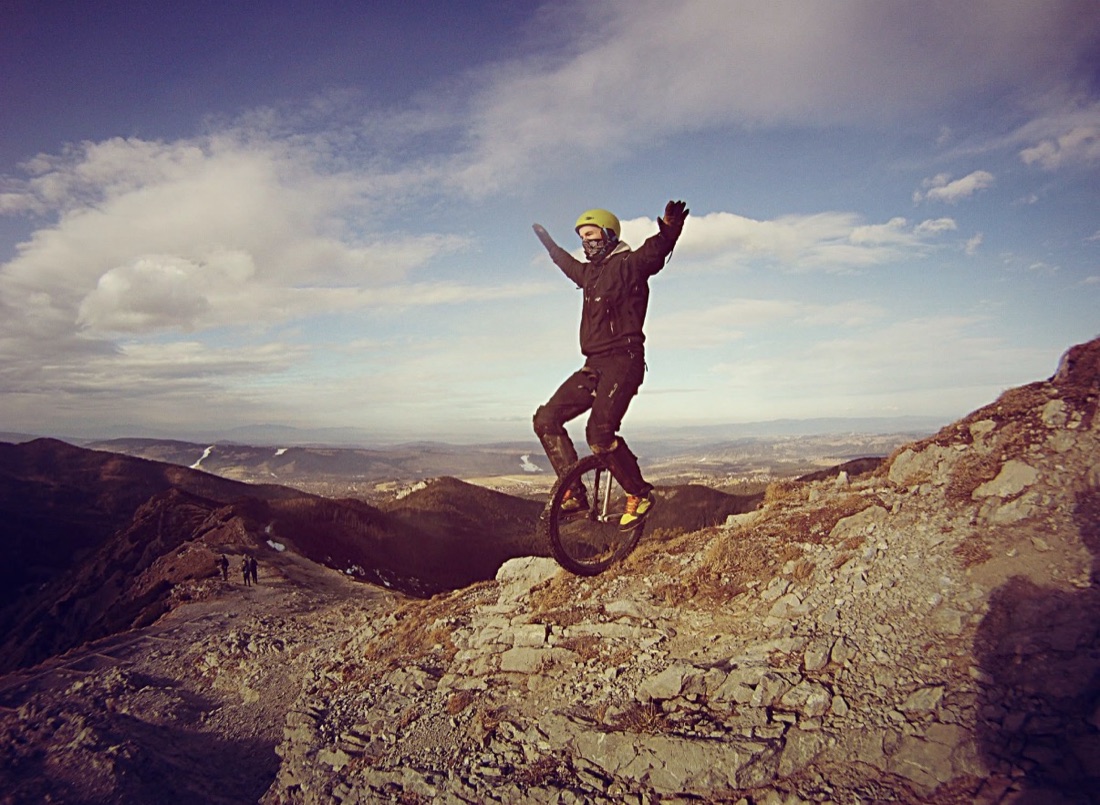 The Pole riding a unicycle on a mountain ridge